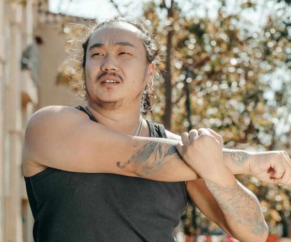 Man stretching outdoors, looking serene and focused on his well-being.
